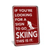 Rustic red metal skiing sign reading If You're Looking for a Sign to Go Skiing This Is It with skier silhouette