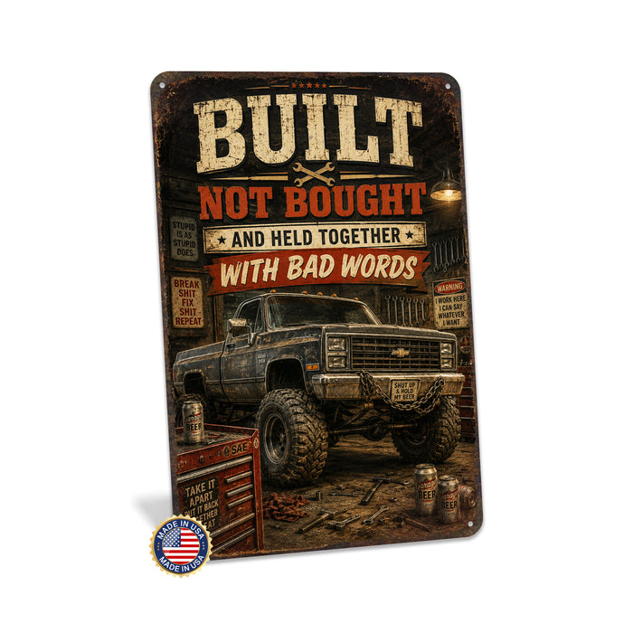 Built Not Bought Truck Garage metal sign with vintage layout with lifted square-body Chevy K10 on mud tires, tool chest