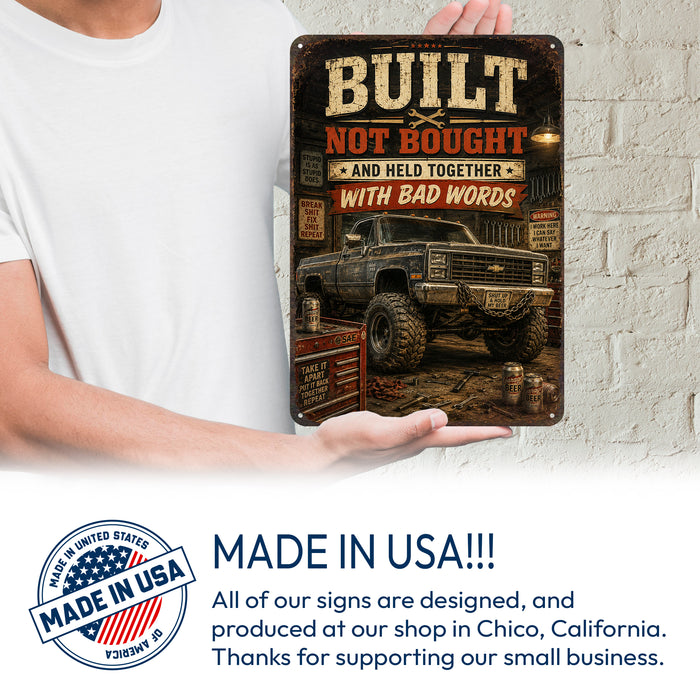Built Not Bought Truck Garage metal sign with vintage layout with lifted square-body Chevy K10 on mud tires, tool chest